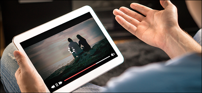 Les mains d'un homme tenant une tablette affichant un "chargement" icône sur une vidéo.