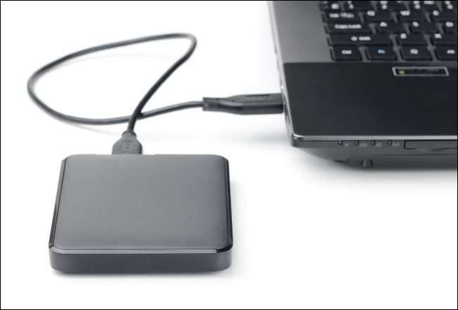 Un disque dur externe connecté à un ordinateur portable via un câble USB.