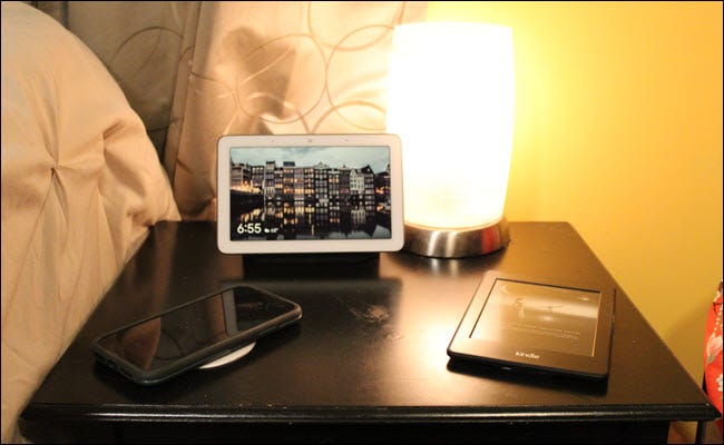 Nest Hub, Kindle et iPhone sur une table de nuit.