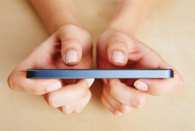 Deux pouces de mains féminines tapant sur un smartphone