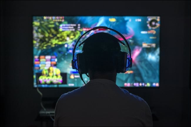 Un jeune joueur jouant à un jeu PC tout en portant des écouteurs.