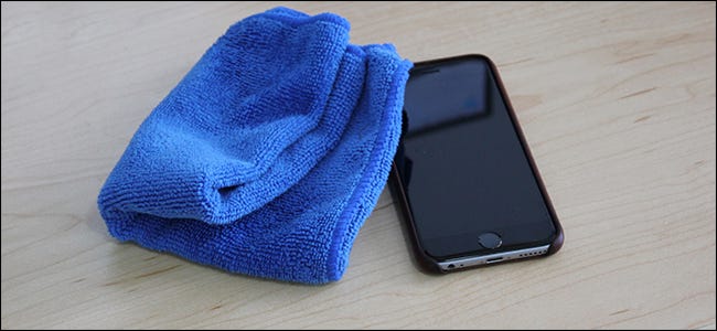 Un chiffon en microfibre bleu assis à côté d'un iPhone. 