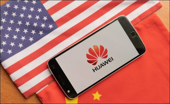 Un téléphone Huawei entre un drapeau américain et chinois.