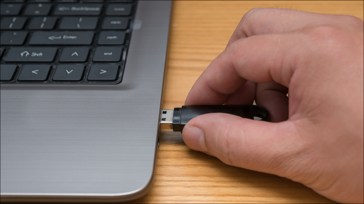 La main d'une personne connectant une clé USB à un ordinateur.