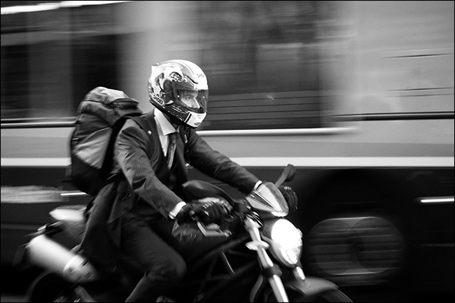 Homme en costume moto avec bus flou se déplaçant derrière lui